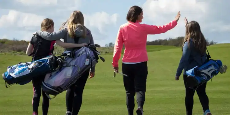 Join Wales Golf Day on June 7th & Help Break a National Record Welsh golfers pictured on the fairway carrying their golf clubs.