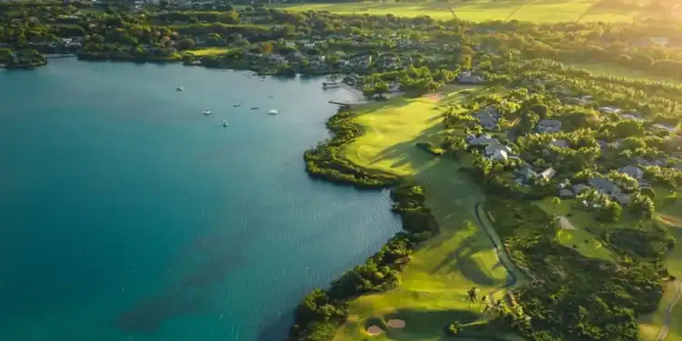 Anahita Golf & Spa Resort Welcomes New Management Partner A golf course with a body of water and a hill in the background.