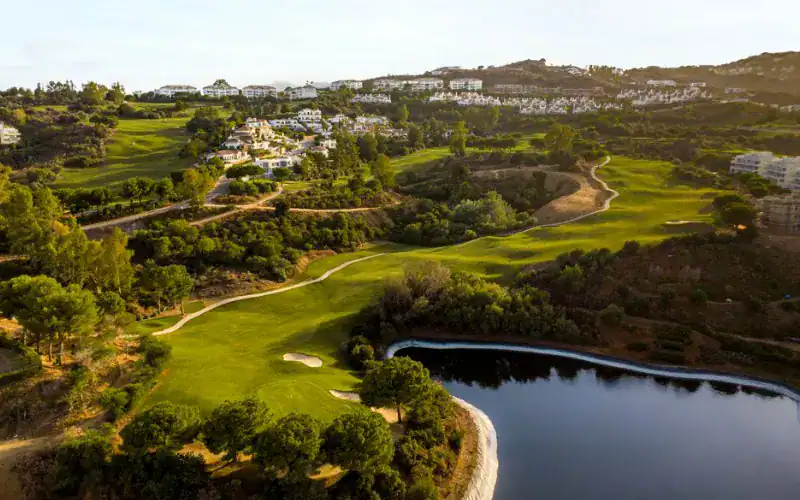 La Cala Resort Expands Golf Experience with New Short Course a golf course with a body of water and a town in the background