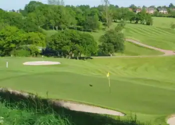 Dean Wood Golf Club Society Golf Day Deals This image shows a smoothly contoured putting green in the foreground, bordered by a bunker, with gently rolling fairways and another bunker visible further back.