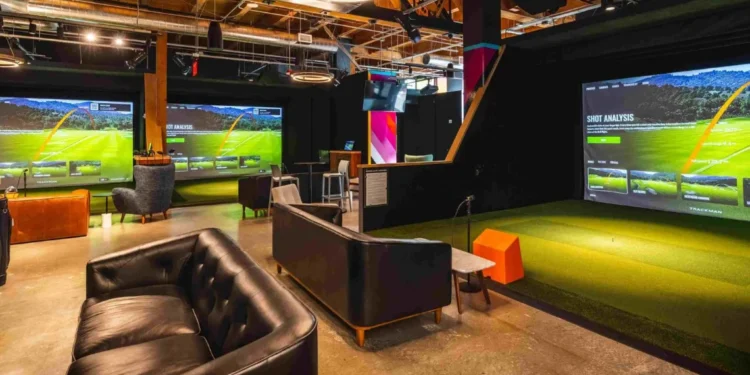 Five Iron Golf to Open Indoor Golf Venue in Riyadh in 2026 A room with a large golf simulator screen and a couch.