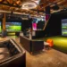 Five Iron Golf to Open Indoor Golf Venue in Riyadh in 2026 A room with a large golf simulator screen and a couch.