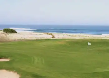 A golf course with a flag on the beach.