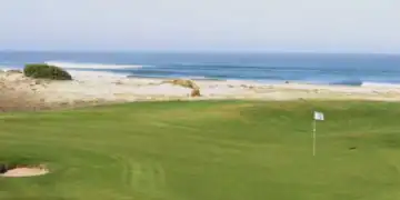 A golf course with a flag on the beach.