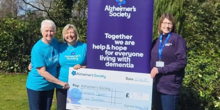 Helsby Captain Raises £5,719 for Alzheimer’s Society a group of women standing next to a large sign