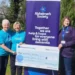 Helsby Captain Raises £5,719 for Alzheimer’s Society a group of women standing next to a large sign