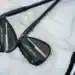 Titleist Reveals Vokey SM10 Black Vapor Wedges for 2025 Close-up of Titleist Vokey SM10 Black Vapor wedges with black finish, resting on a white golf towel.