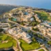 Aphrodite Hills Launches Major Investment Plan a aerial view of a town with a pool and a body of water