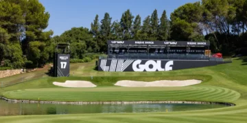 a golf course with a pond and a large black sign