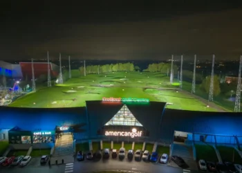 Late Nights, More Golf: Trafford Golf Centre Extends Hours! a building with a golf course and cars parked in front of it