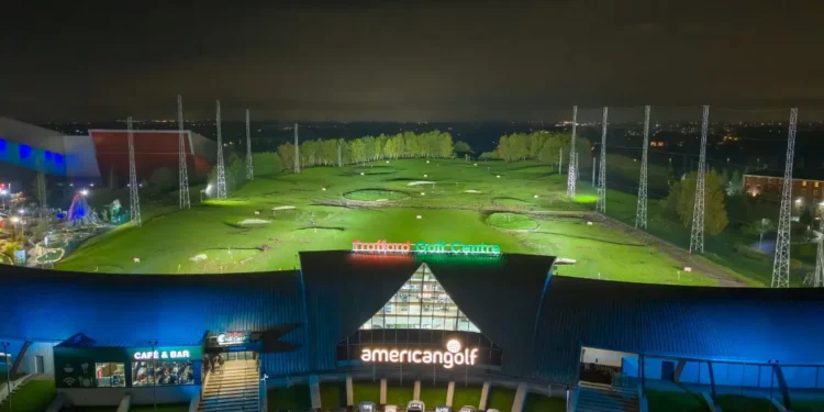 Late Nights, More Golf: Trafford Golf Centre Extends Hours! a building with a golf course and cars parked in front of it
