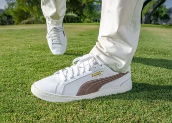 a person's feet in white shoes on grass