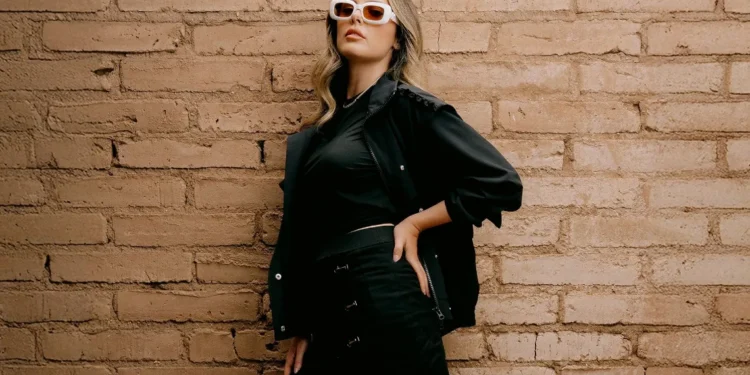PXG Launches Fall Winter 2025 Apparel Collection Stylish woman against textured brick wall.