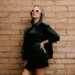 PXG Launches Fall Winter 2025 Apparel Collection Stylish woman against textured brick wall.