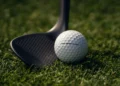 Golf ball and club on grass.